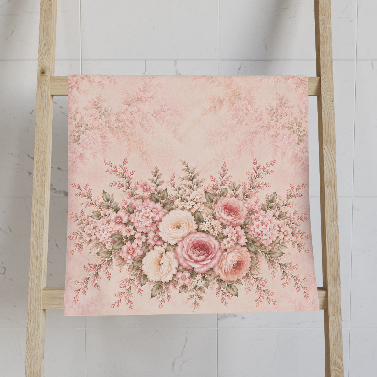 A hand towel featuring a vintage-style floral bouquet print in shades of pink, cream, and green, draped over the side of a light wood ladder against a white marble-look tiled wall.